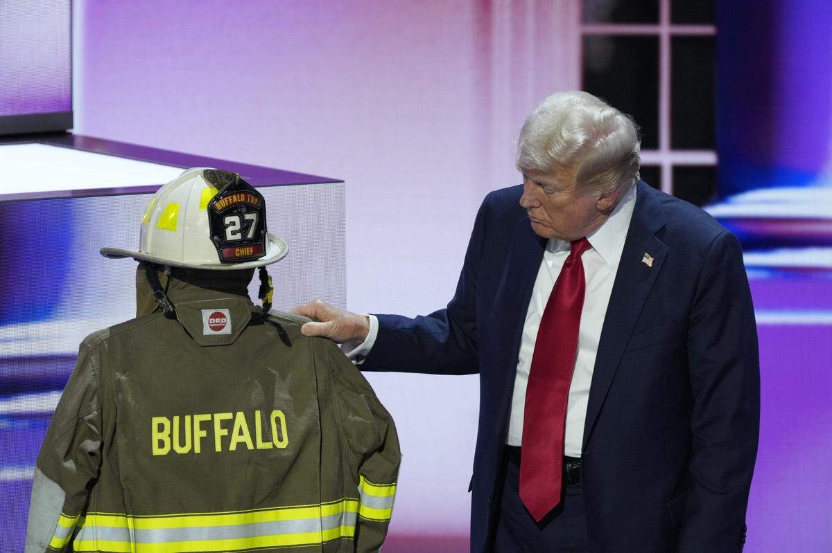 July 18, 2024; Milwaukee, WI, USA; Republican presidential nominee Donald J. Trump looks at the uniform of former fire fighter Corey Comperatore, who was killed at the Butler rally, before delivering his nomination acceptance speech during the final day of the Republican National Convention at the Fiserv Forum. The final day of the RNC featured a keynote address by Republican presidential nominee Donald Trump. Mandatory Credit: Mike De Sisti-USA TODAY