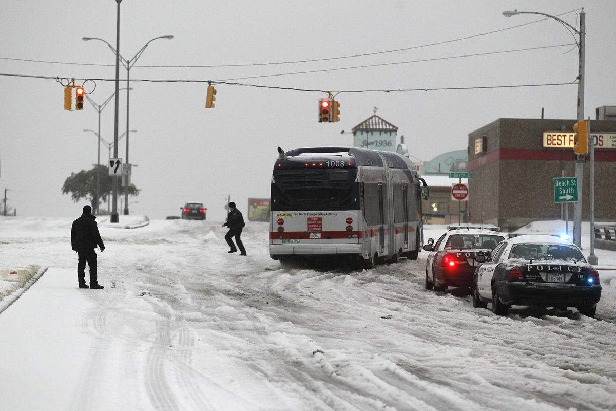 Fort Worth police try to control traffic around a city bus stuck in ice on East Lancaster Avenue in Fort Worth, Texas, on Friday, Dec. 6, 2013.