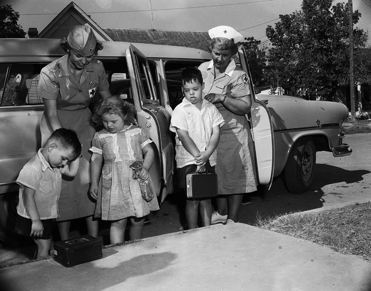 Sept. 14, 1953: Three students of the Fort Worth Opportunity Center, located at East Van Zandt Elementary School, prepare to board a Red Cross station wagon. The Red Cross is providing transportation where needed for students attending the center. Mrs. Julian Read, left, motor service driver, and Mrs. Wanda Neely, Red Cross gray lady, took the youngsters home after the first day of classes.