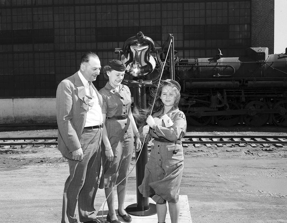 March 15, 1950: W.F. Kascal of Dallas, mechanical superintendent for the Texas & Pacific Railway, presents a shined and polished engine bell to the Girl Scouts for a dinner gong at Camp Timberlake. The girls are Gail Wills, center, senior scout from Troop 35, and Gretchen Von Rosenberg of Troop 101.