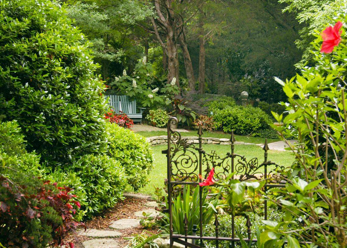 This backyard still has a focal point even though it is separated by shrubs and an antique wrought iron gate.