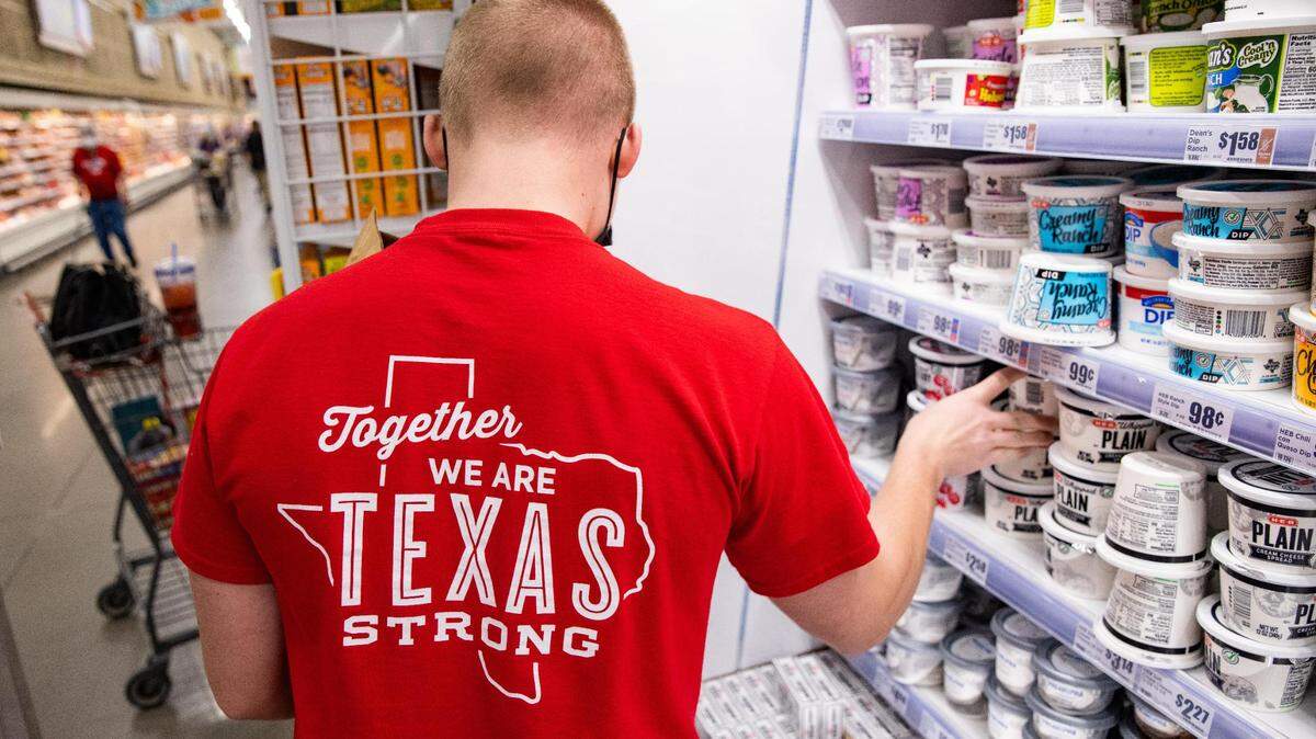 H-E-B employee Tyler Land restocks the dairy section at the grocery store Hudson Oaks in 2021. His red T-shirt shows the state of Texas with the words: "Together we are Texas strong." 