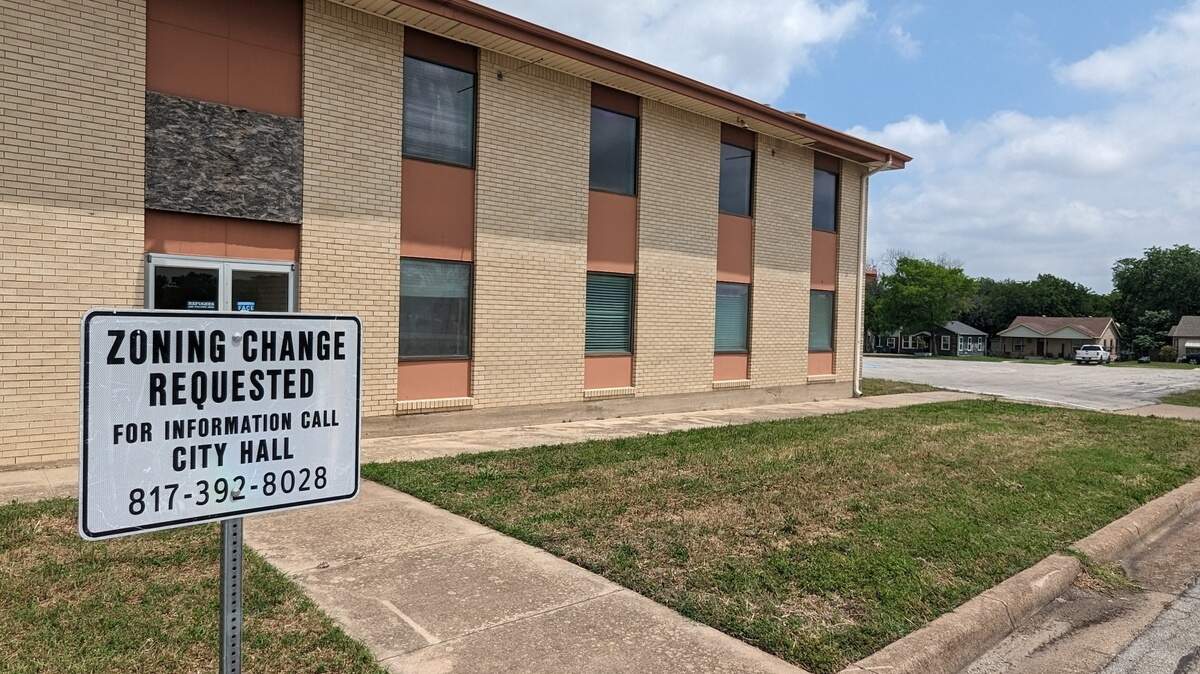 A shot of a building with a "zoning change requested" sign in front. 