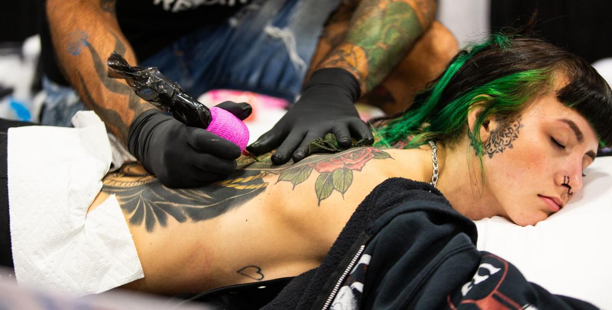 Baltimore resident Kenzie lays on a table while getting a tattoo during Fort Worth Tattoo Arts Festival on Friday, June 7, 2024, at the Fort Worth Convention Center. Kenzie has been tattooing for a year and a half, working with traditional style designs, while working with her dad who is also a tattoo artist.