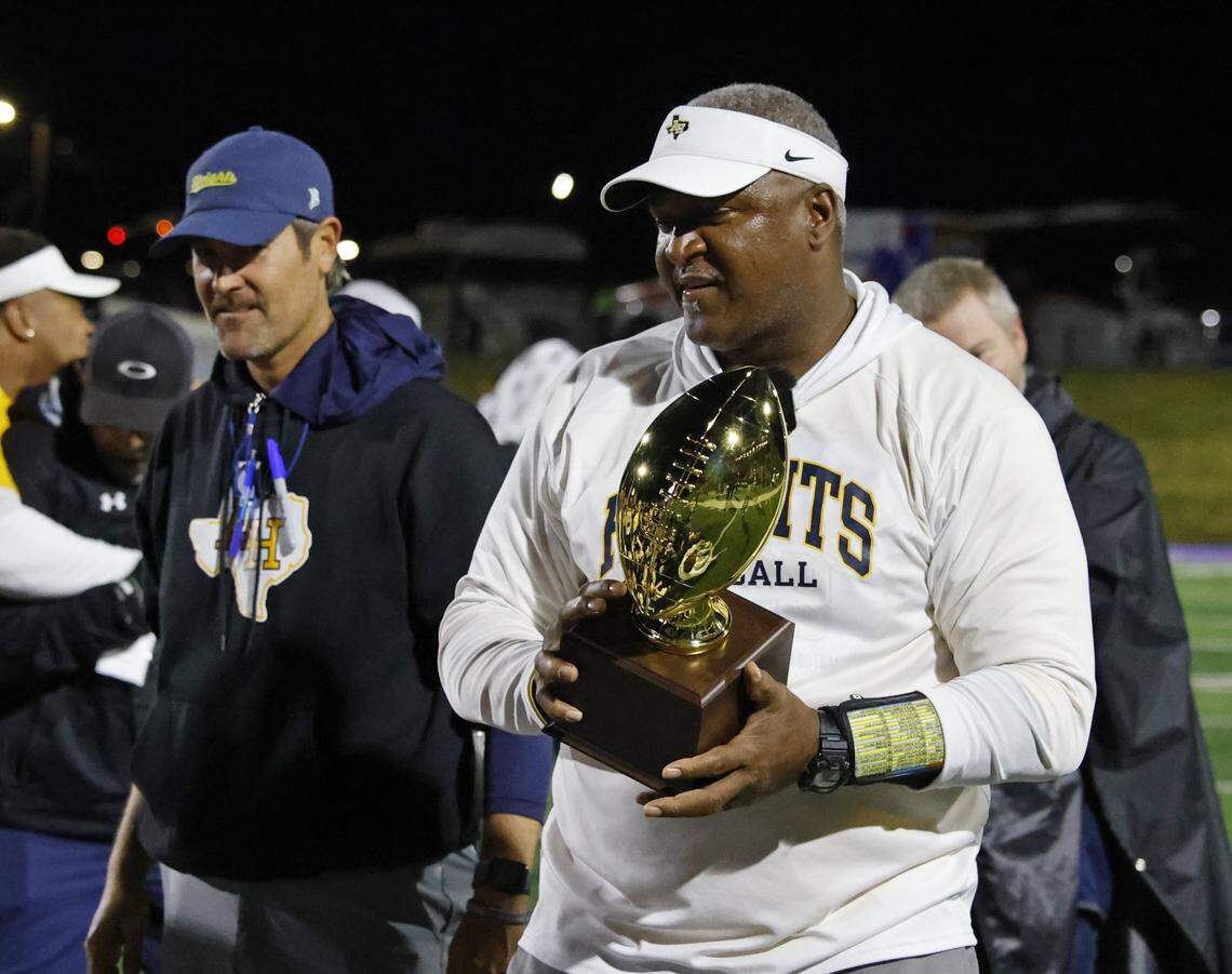 Fort Worth Arlington Heights head coach Curtis James carries the area-round trophy after a Class 5A Division I playoff victory over Lubbock Monterey on Thursday at Shotwell Stadium in Abilene.