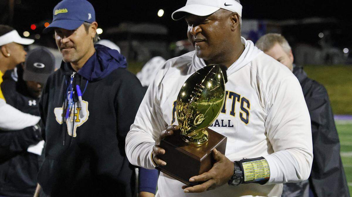 Fort Worth Arlington Heights head coach Curtis James carries the Class 5A Division I area-round football championship trophy after a playoff win against Lubbock Monterey on Nov. 20 at Shotwell Stadium in Abilene.