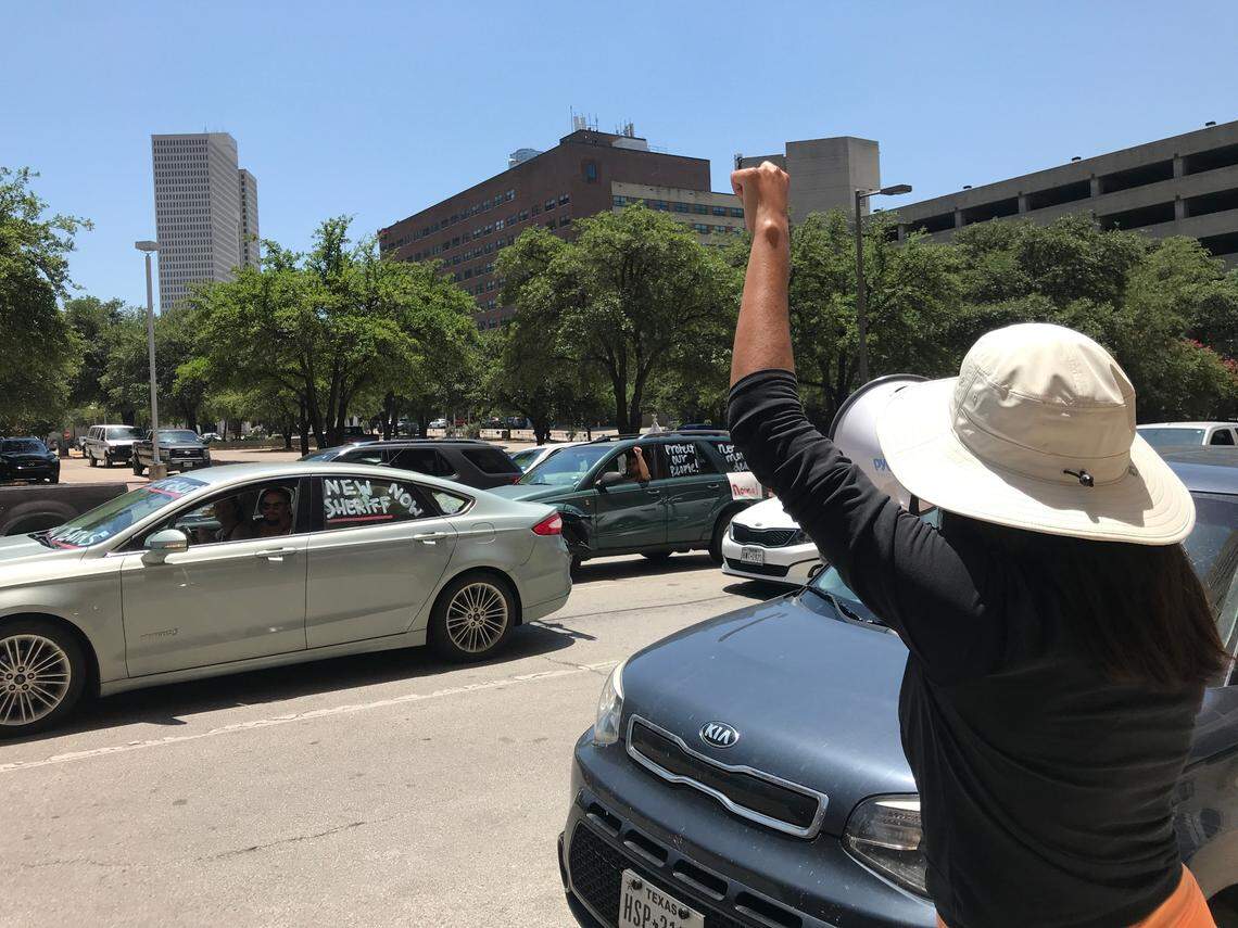 Sindy Mata, 25, shouts into a megaphone as cars drive around the Tarrant County Jail on Saturday to protest recent deaths and conditions at the jail. She was one of the organizers of the event in which protesters stayed in their cars in the interest of maintaining social distance.