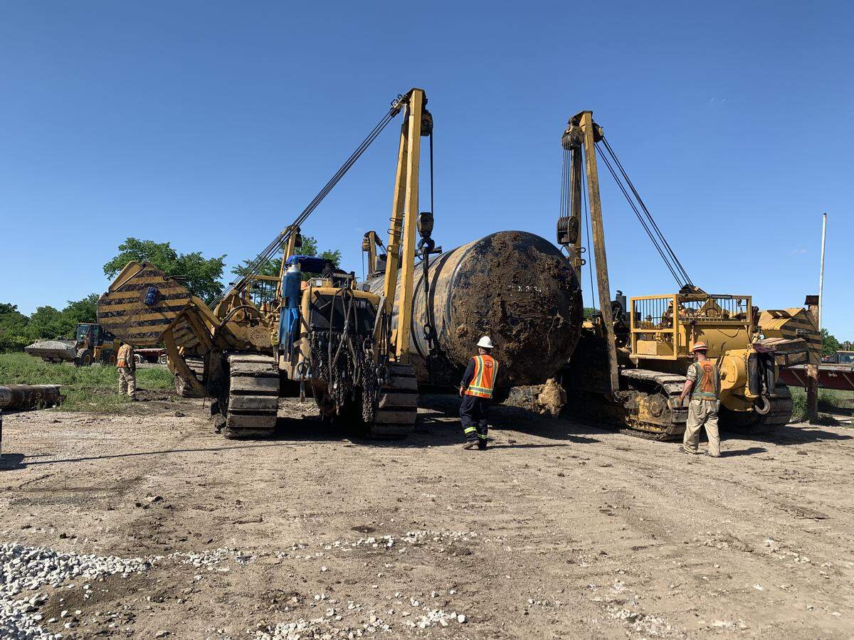 Workers use heavy equipment to move a damaged tanker car from railroad tracks in south Fort Worth.