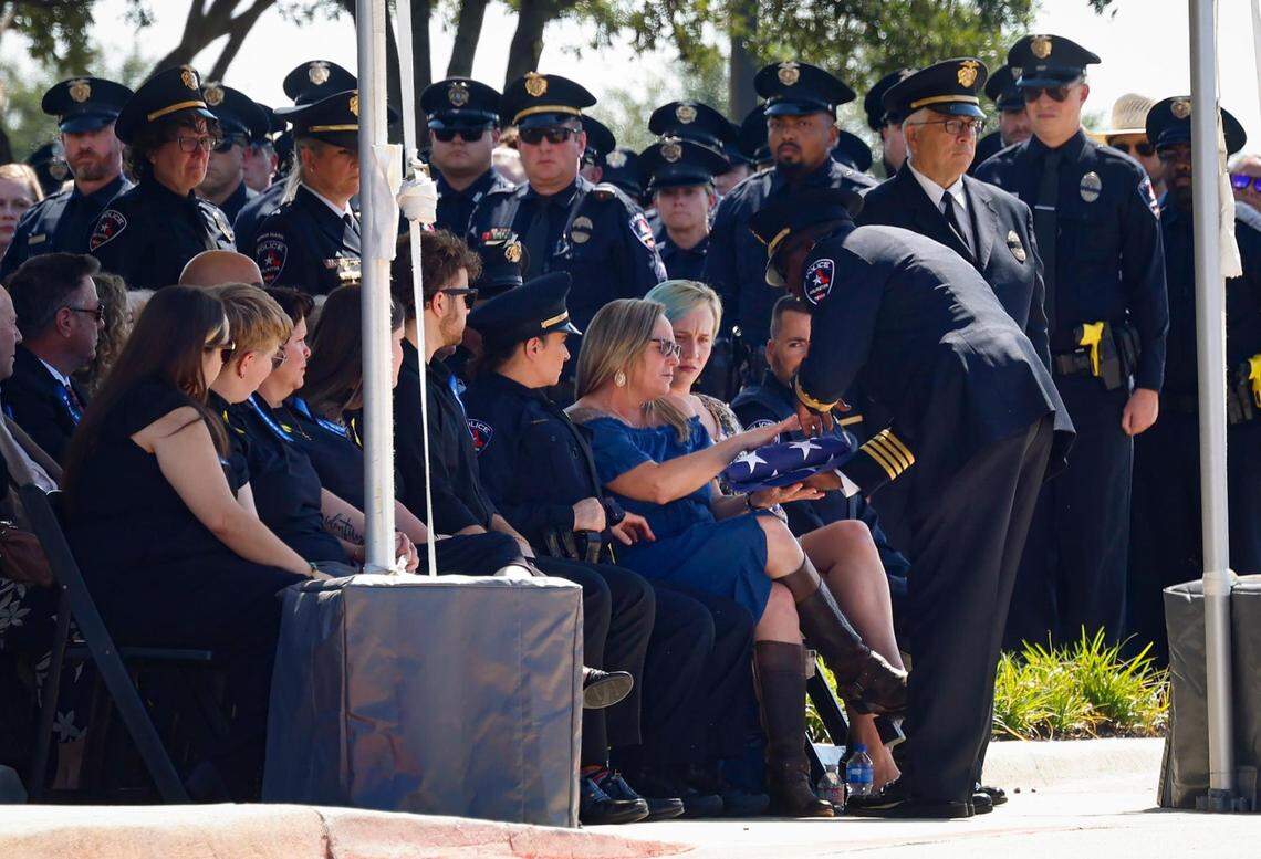 Arlington Police Chief Al Jones presents the American flag to Lynette Rachelle Holland McMichael, the wife of Darrin McMichael, on Wednesday, September 27, 2023, at Crossroads Christian Church in Grand Prairie. Darrin McMichael, a member of Arlington’s Motorcycle Unit, was killed on Sept. 21 while on his way to work.