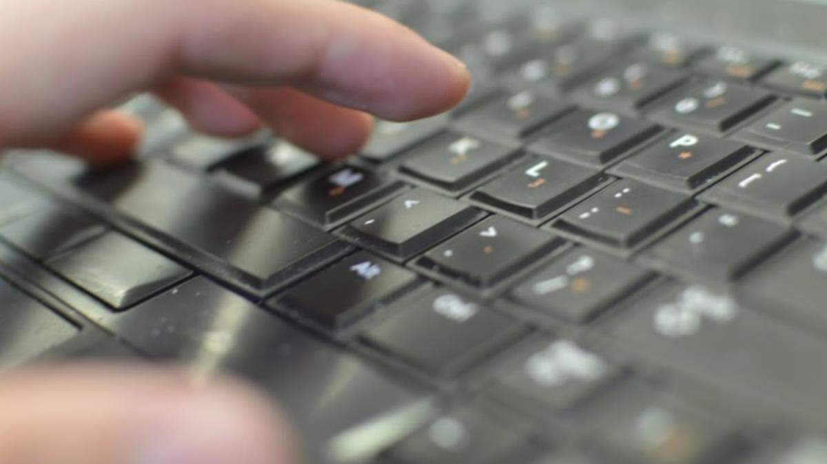 A left hand hovering over a laptop keyboard