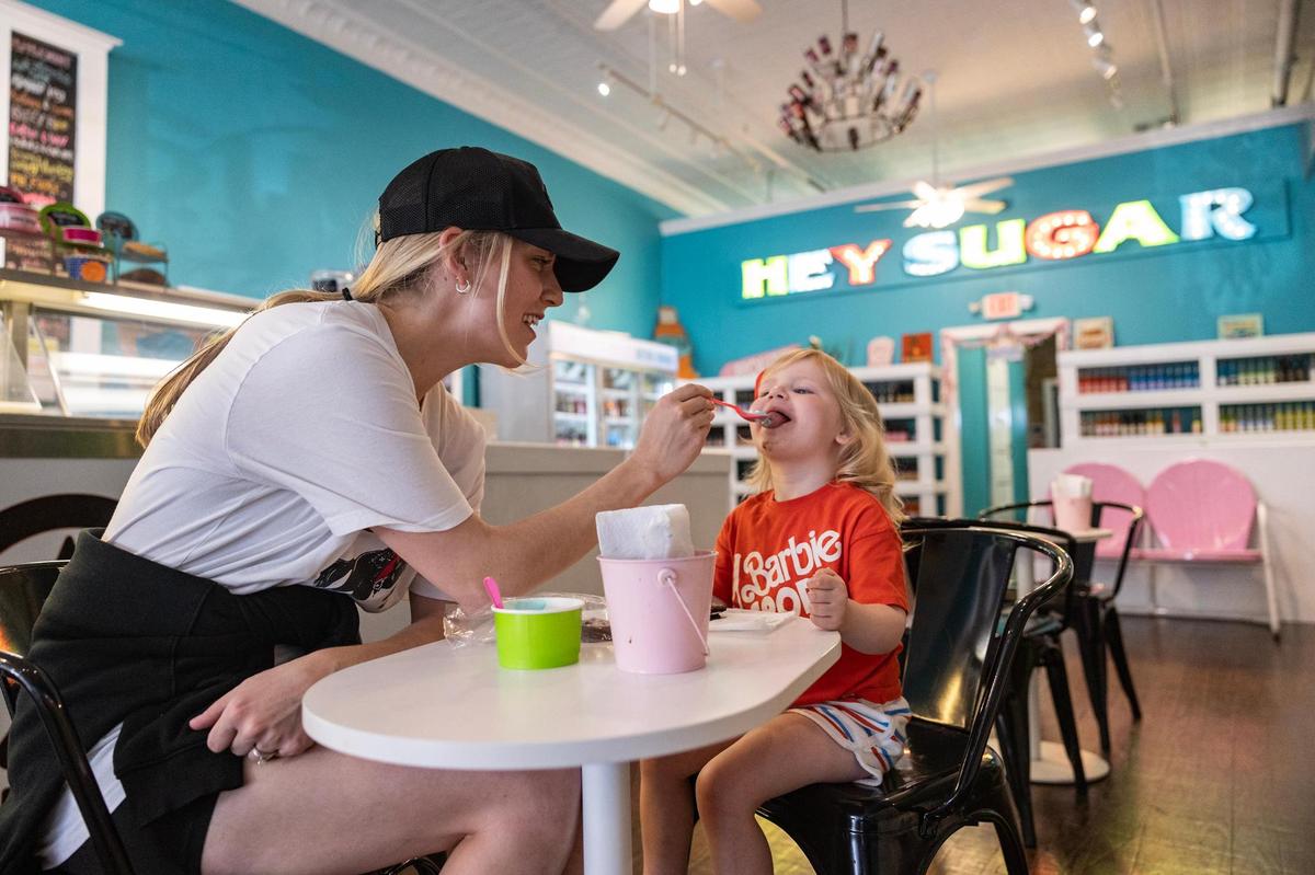 Decatur resident Jacey TIbbels feeds ice cream to her daughter Charlie, 3, at Hey Sugar Candy Store in Decatur on Thursday, March 29, 2025. Tibbels, who has lived in Decatur all her life, feels like the growth could expose younger families to the small-town Texas lifestyle that you can’t get closer to the city.