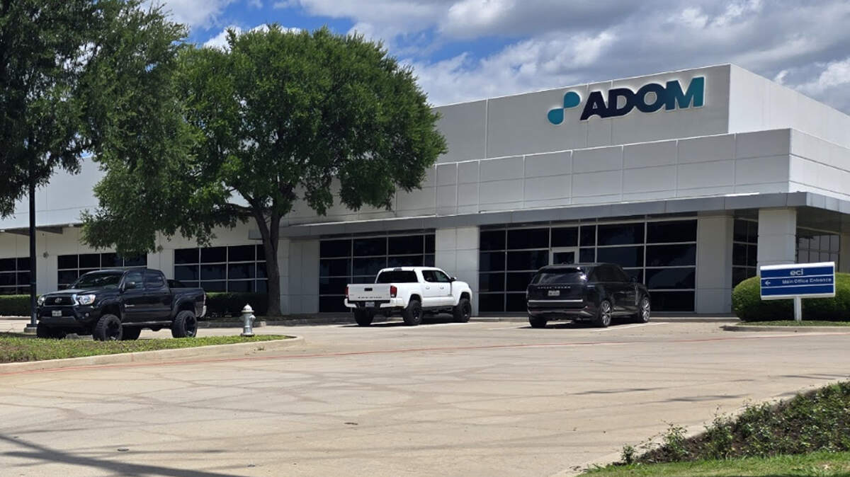 A square building in an office park that says Adom on the outside.