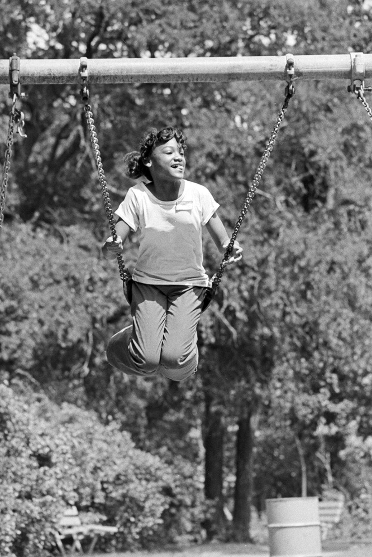 June 17, 1975: Andrea Curley, 12, of Girl Scout Troop 134 swings at Sycamore Park during Juneteenth festivities.