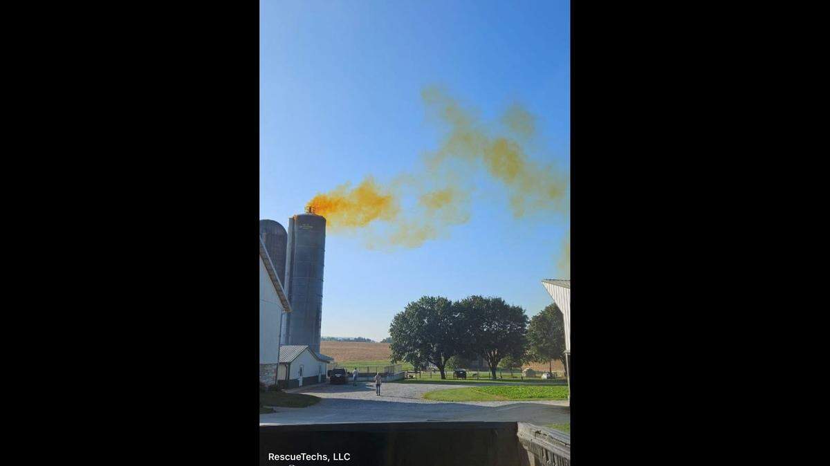 Orange smoke from the silo spews through the air.