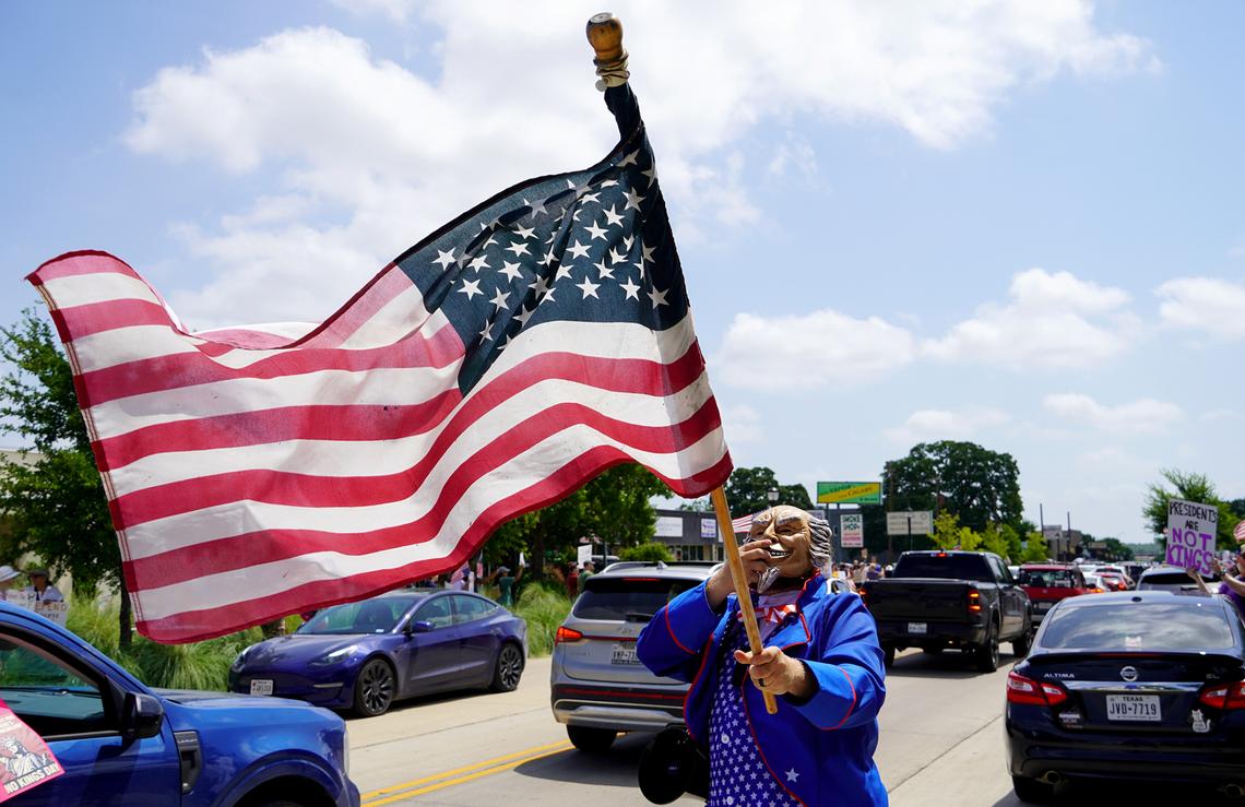 A protesters speaks through a bullhorn on East Abram Street in Arlington for the “No Kings Day” protest on June 14, 2025.