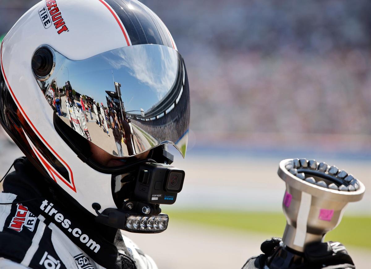 Texas Motor Speedway is reflected off a tire changers face mask during the Auto Trader Echo Park 400 at Texas Motor Speedway in Fort Worth, Texas, April 14, 2024. Kyle Larson won stage 1. (Special to the Star-Telegram/Bob Booth)