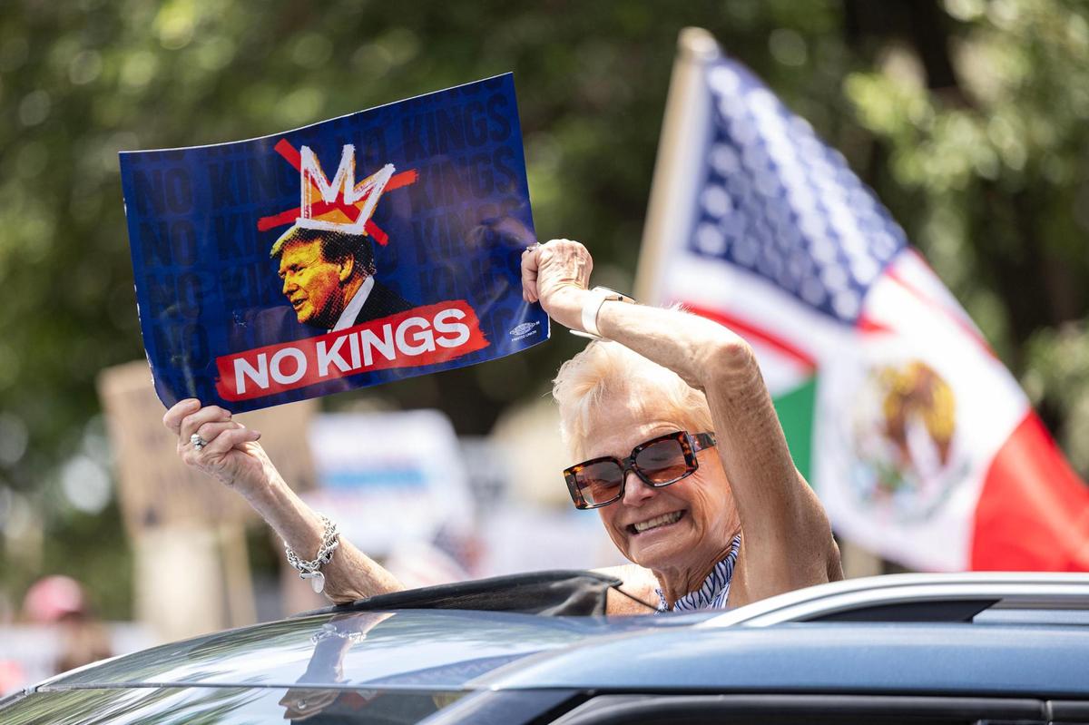 A protester holds a sign outside the car sunroof during the No Kings Protest in downtown Fort Worth on Saturday, June 14, 2025.