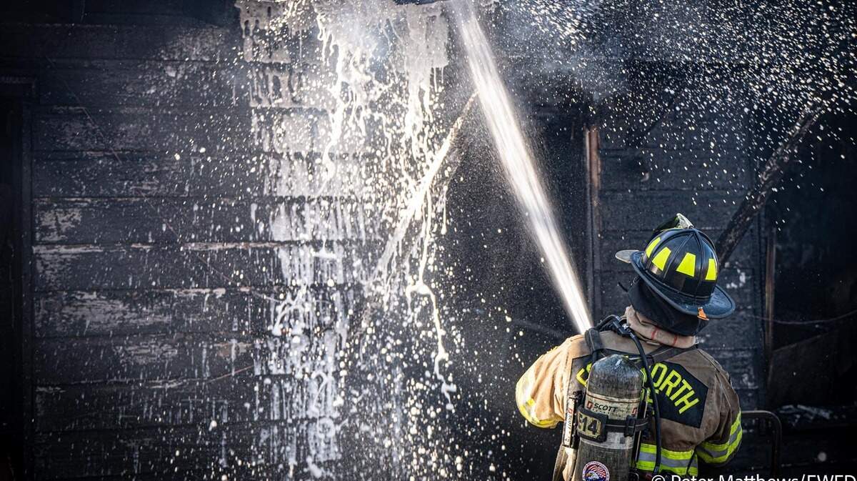 A Fort Worth firefighter battles a blaze at a residence in the 4600 block of Shackleford Street in east Fort Worth on Dec. 31, 2025.