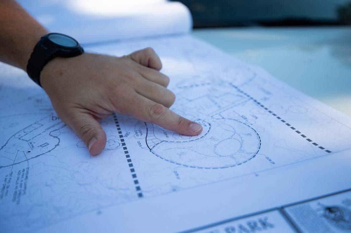 A man points at park design plans on a printed paper.