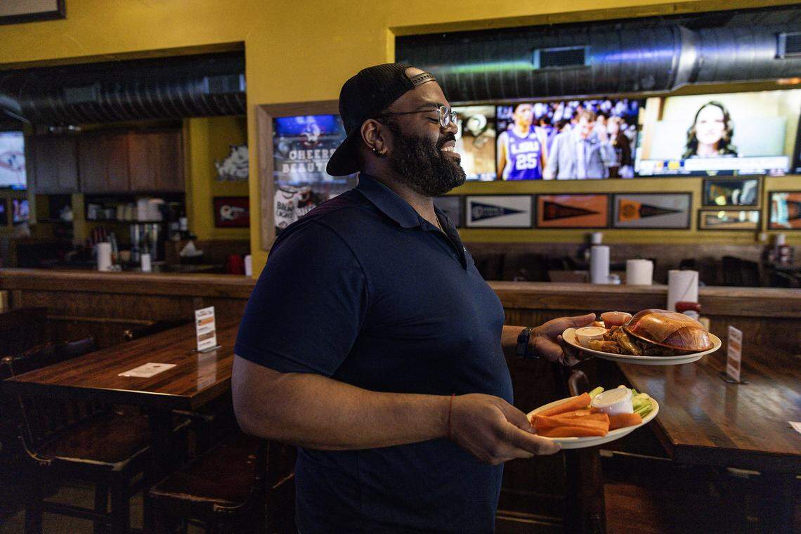 Carl Perkins, the Front of House Manager, serves food to customers during the post lunch rush at Buffalo Bros restaurant near TCU in Fort Worth on Wednesday, Dec. 3, 2025.