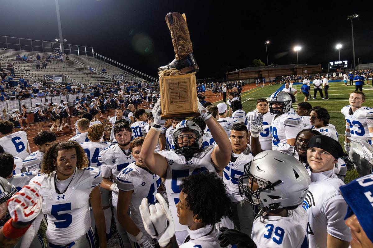 The Burleson Centennial Spartans football team hoists the Boot Bowl trophy after winning the 2024 Boot Bowl game against Burleson High School at BISD Stadium in Burleson on Friday, Aug. 30, 2024. The Spartans defeated the Elk 28-7 to take home the Boot Bowl trophy for the third year in a row.