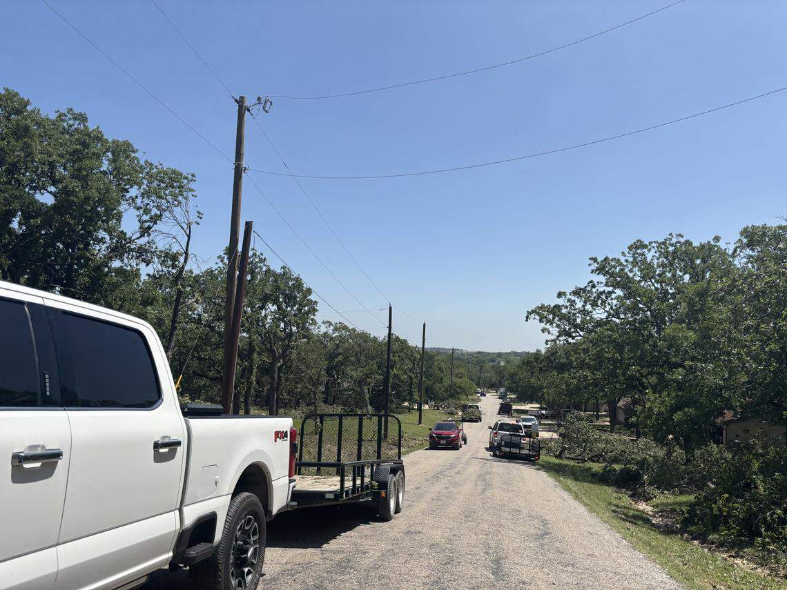About half a dozen trucks hauling trailers down Runaway Bay Drive helped clear tornado debris from yards in Runaway Bay on April 27, 2026.
