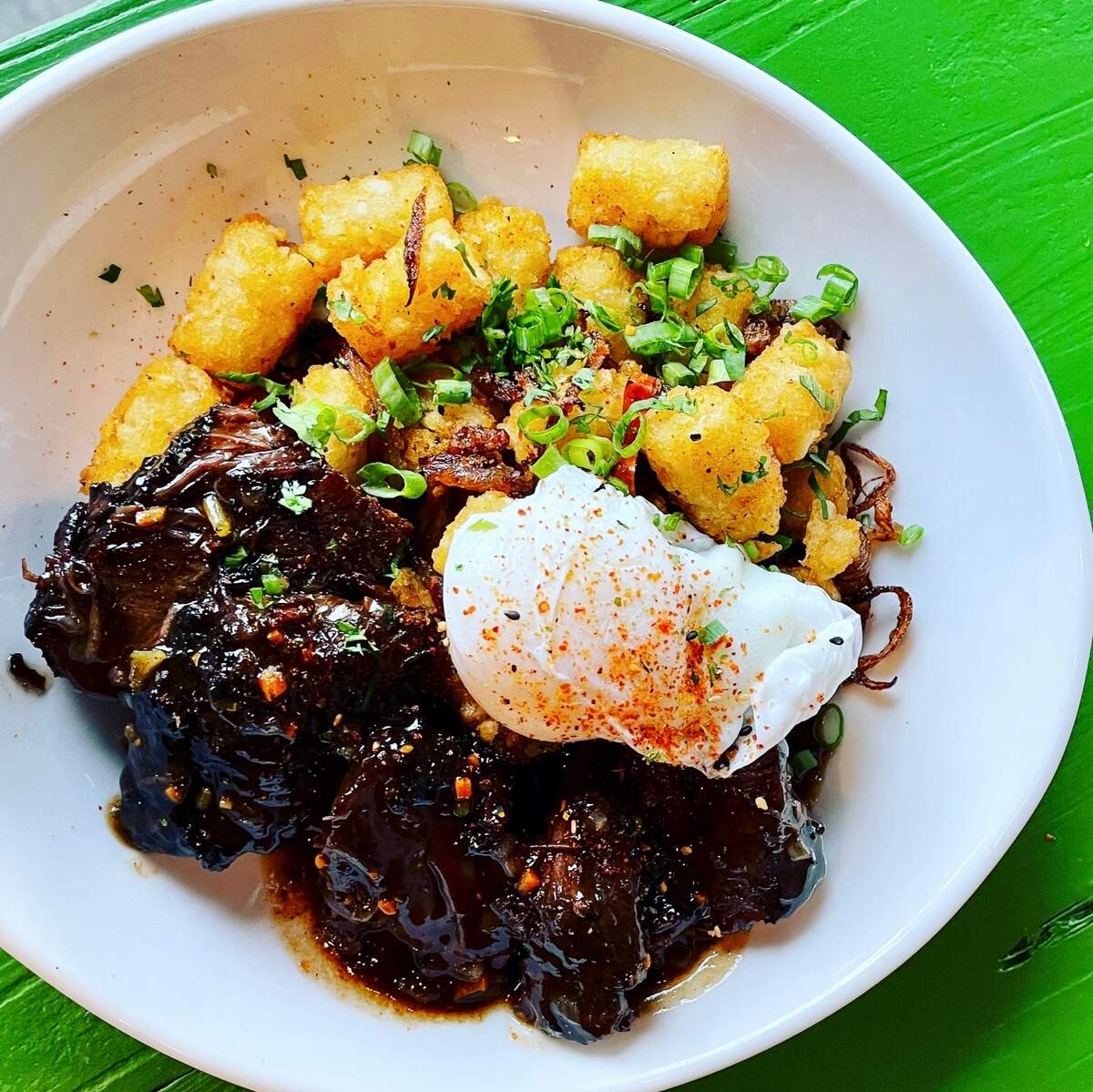 Sichuan braised beef cheek hash with a duck egg and tater tots wih caramelized onions.