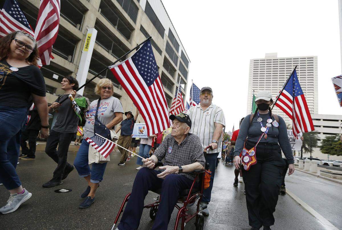 Ninety-five-year-old Korean War veteran William Johnson is participating, along with a large crowd, as they march through downtown streets during the No Kings Rally in Fort Worth on Saturday, Oct. 18, 2025.