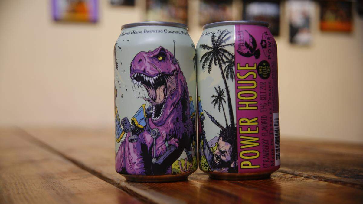Two cans of THC seltzer with a picture of a robotic dinosaur on them sit on a table.