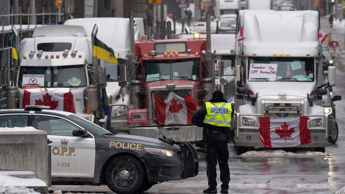 Police man a barricade in front of vehicles parked as part of the trucker protest, Tuesday, Feb. 8, 2022, in Ottawa’s downtown core. Canadian lawmakers expressed increasing worry about protests over vaccine mandates and other COVID restrictions after the busiest border crossing between the U.S. and Canada became partially blocked.