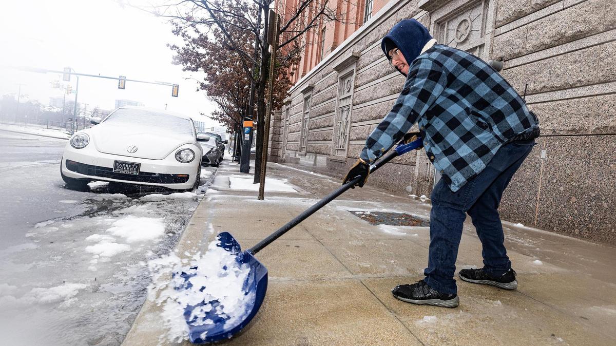 Tarrant County employee Jacob Hernandez shoves snow off the sidewalk in front of the Tarrant County Sheriffs Department Jail in downtown Fort Worth on Thursday, Jan. 9, 2025.