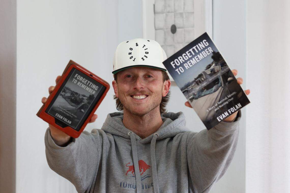Evan Folan, wearing his brain injury awareness clothing brand, is holding his newly published memoir, “Forgetting to Remember.”