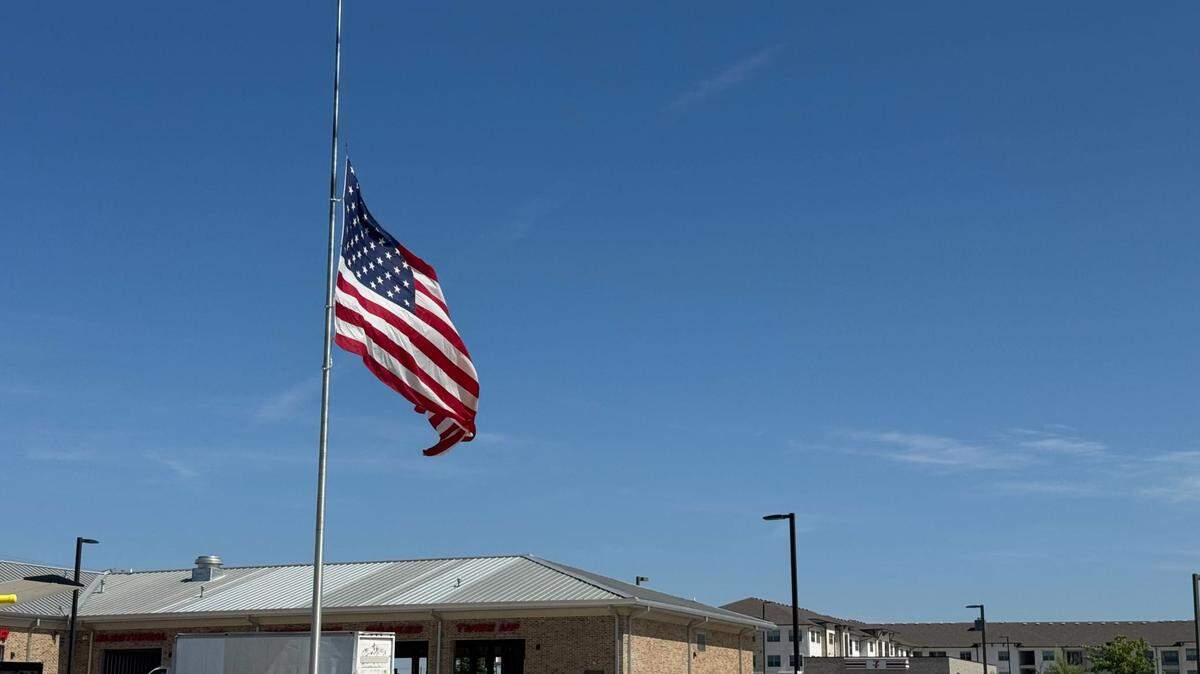 A large American flag flies at half mast Friday at an auto service center on Harmon Road in far north Fort Worth.