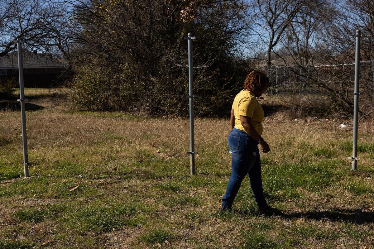 Smith walks by fence poles pitched in the backyard of her new home in southeast Fort Worth.