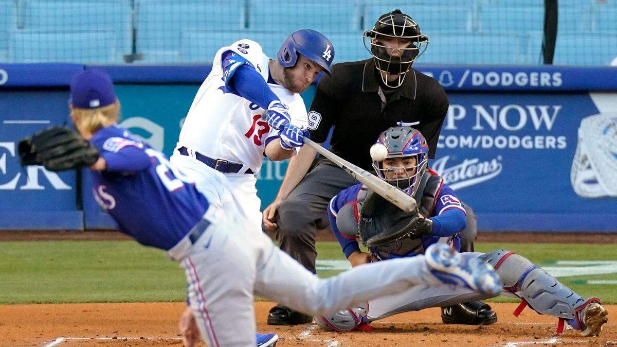 Los Angeles Dodgers’ Max Muncy, second from left, hits a solo home run as Texas Rangers starting pitcher Mike Foltynewicz, left, and catcher Jose Trevino, right, watch along with home plate umpire Nic Lentz during the first inning of a baseball game Friday, June 11, 2021, in Los Angeles. (AP Photo/Mark J. Terrill)