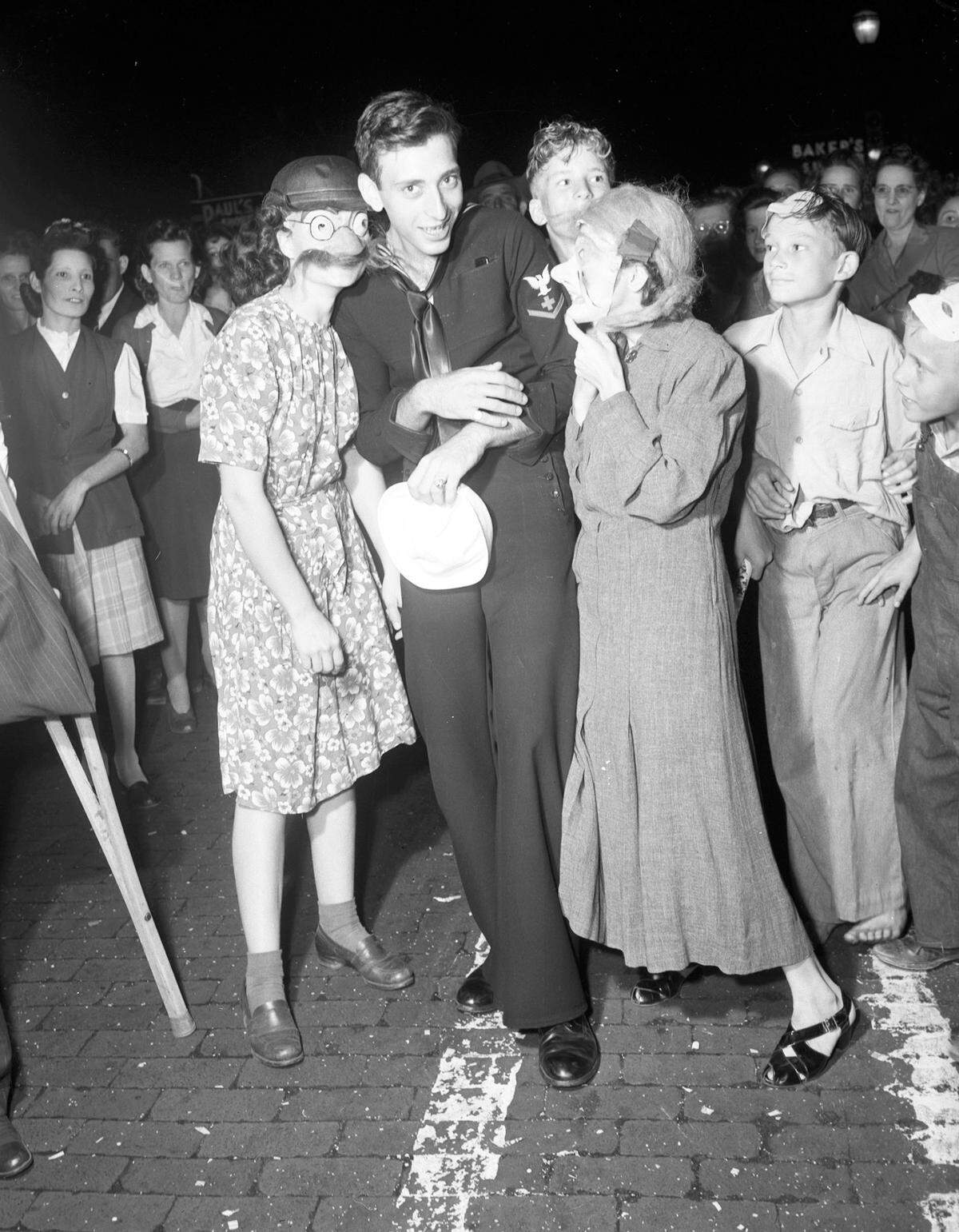 An unidentified sailor and two young ladies celebrate Halloween in 1945.