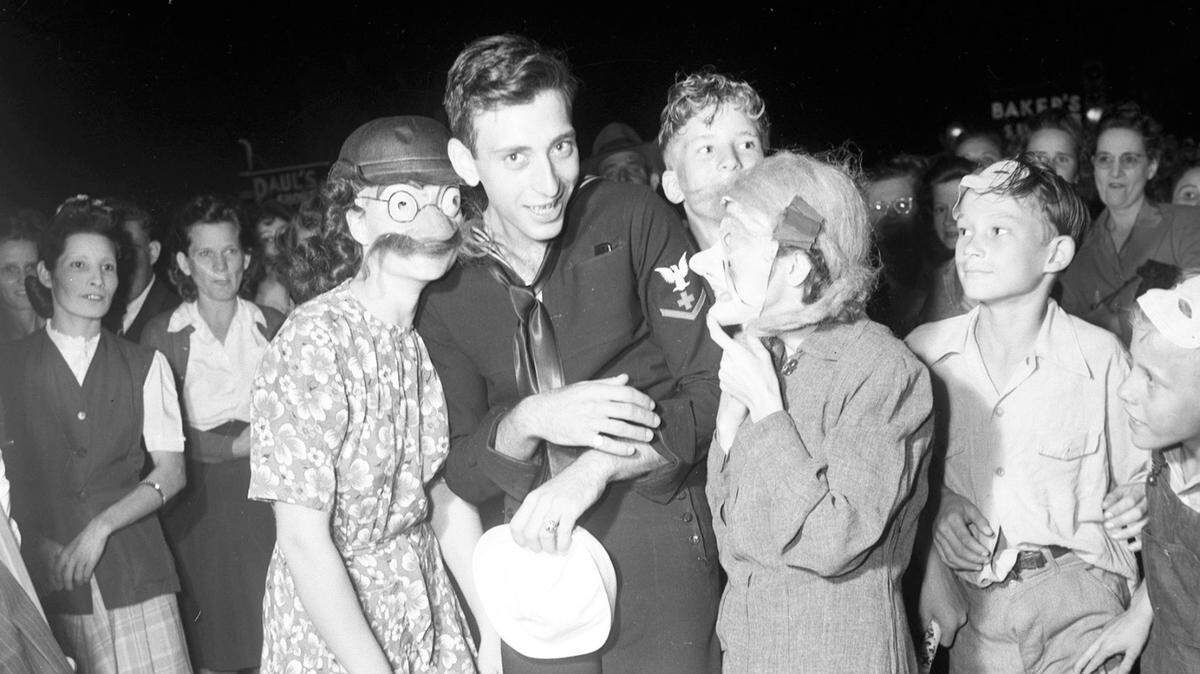 An unidentified sailor and two young ladies celebrate Halloween in 1945.