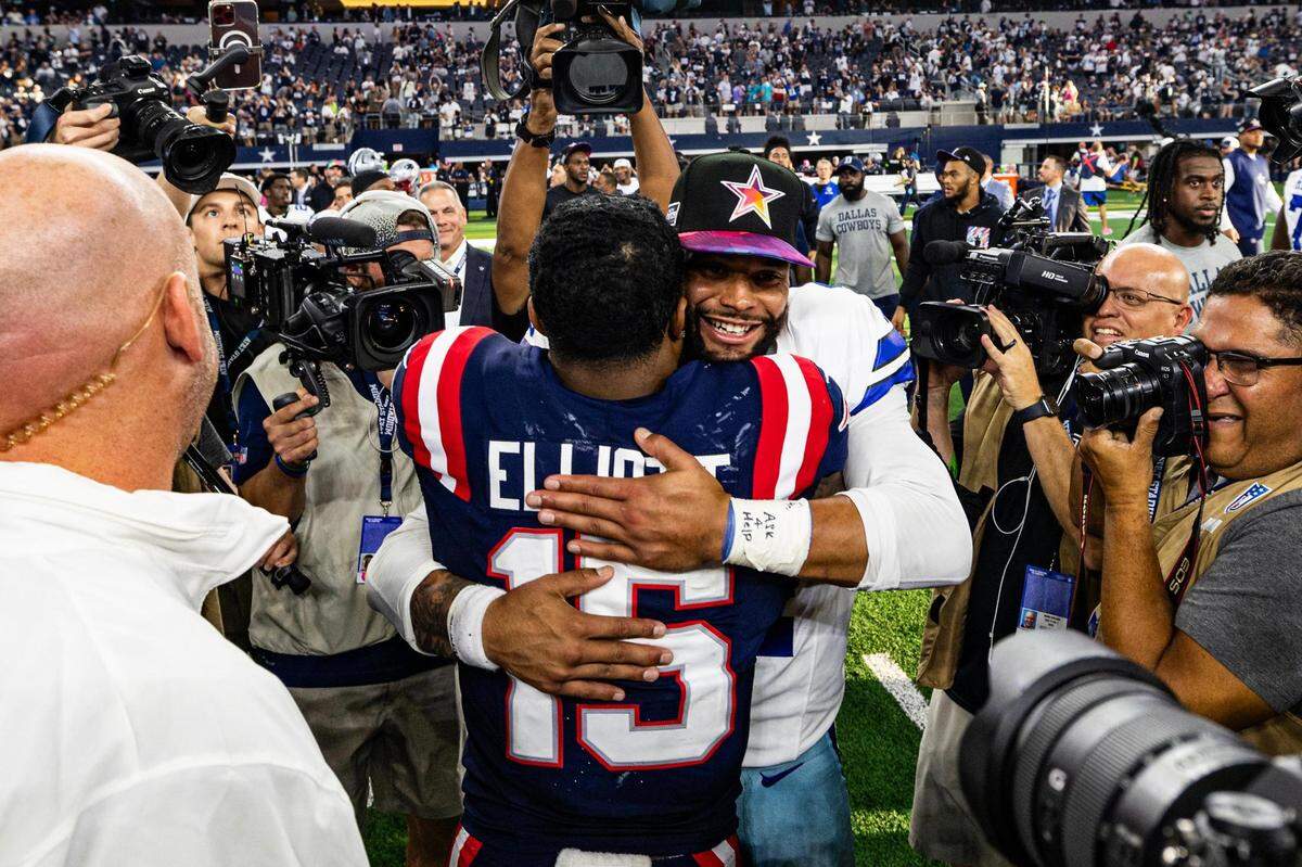 Former teammates Ezekiel Elliot (15) and Dak Prescott (4) embrace after an NFL game between the Dallas Cowboys and New England Patriots at AT&T Stadium in Arlington on Sunday, Oct. 1, 2023. The Cowboys won 38-3 in their reunion.