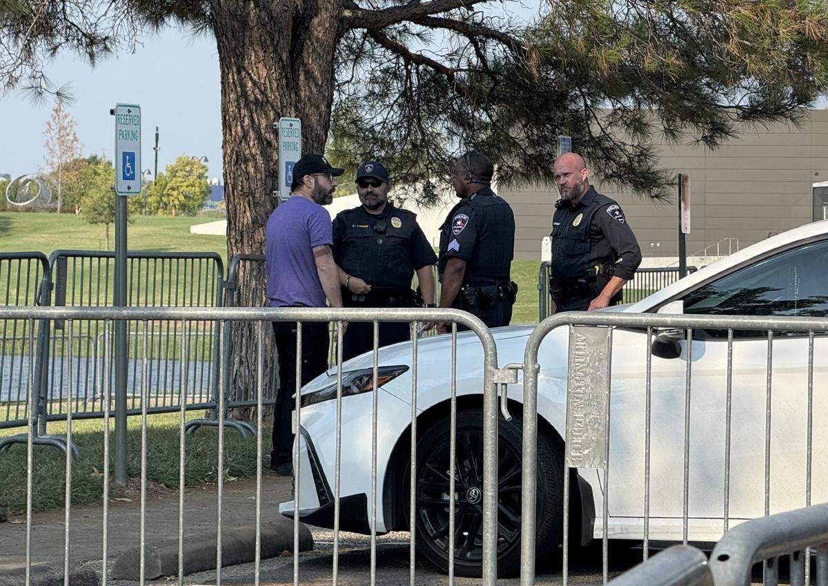 Police officers speak with Eddie Delgado, left, of Indivisible Fort Worth after he said he was assaulted by a man in the parking lot while protesting outside of an ICE job fair in Arlington on Wednesday, Aug. 27, 2025.
