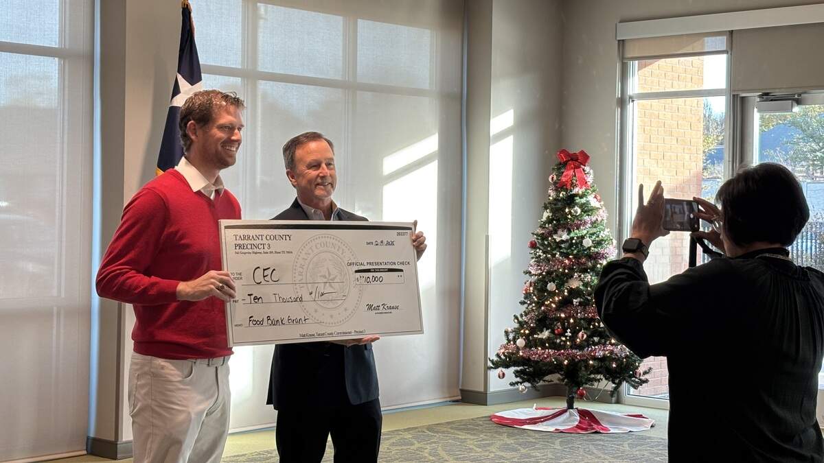Commissioner Matt Krause presents a $10,000 check to Community Enrichment Center CEO Bryan Downer who said the money will give 400 families two weeks’ worth of food.