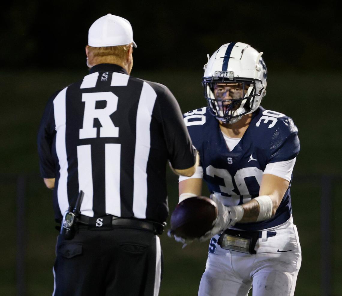 All Saints defensive end Dalton Knapp (30) hands the ball to referee Karl Wright during a TAPPS football game at All Saints High School’s McNair Stadium in Fort Worth Thursday, Sept. 12, 2024.