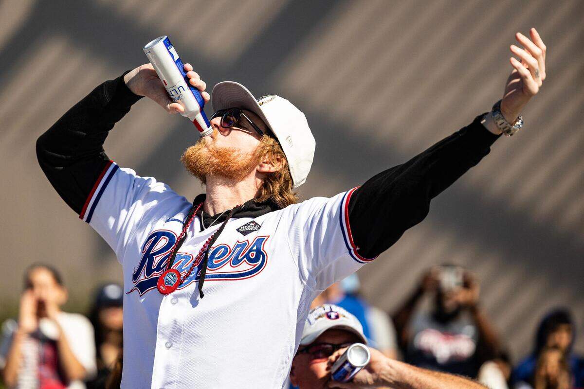 Rangers pitcher Jon Gray hugs a beer and celebrates with the crowd for the World Series Parade in front of Globe Life Field in Arlington on Friday, Nov. 3, 2023.