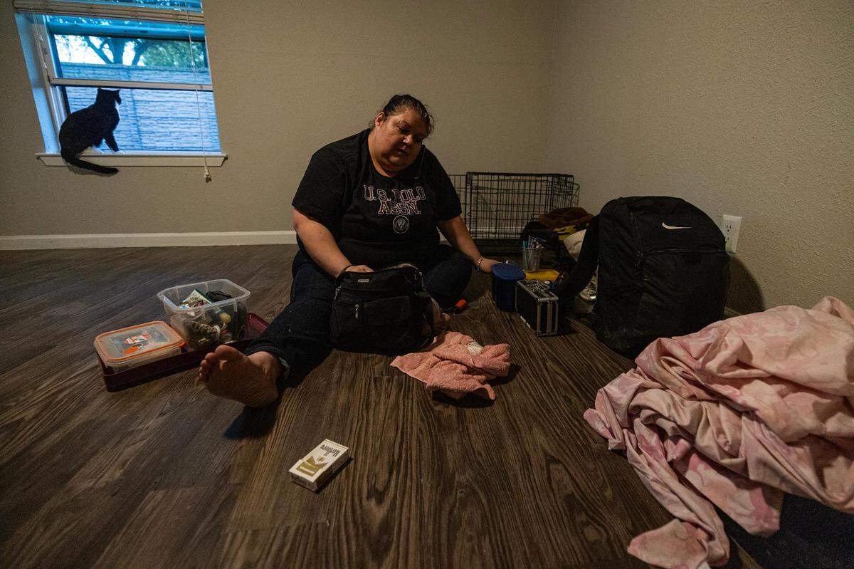 Amber Rogers, Carol Rogers daughter-in-law, talks on phone with her husband Matthew accompanied by her cat Phoenix as she begins to sort through her belongings in her new apartment in Saginaw on Tuesday, Nov. 21, 2023.
