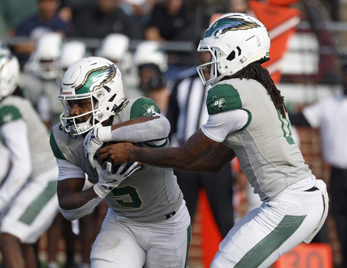 DeSoto quarterback Legend Howell (right) hands off to running back SaRod Baker against Southlake Carroll during the first half of a Class 6A Division II state semifinal Saturday at Newsom Stadium in Mansfield.