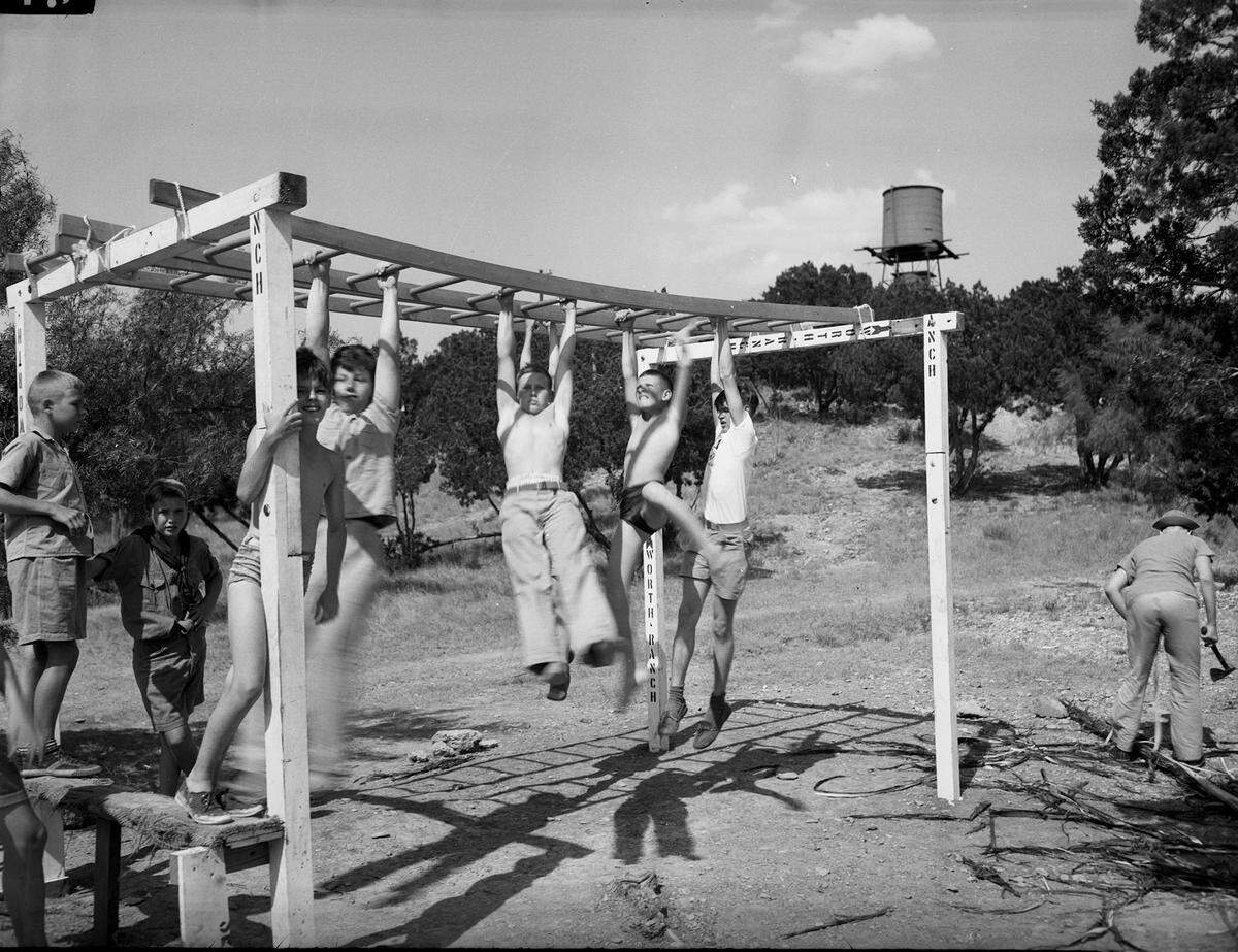July 4, 1943: Pittman Mauldin and Charles Bowman of Fort Worth, and Bill Lynch of Weatherford, cross the hand-walk ladders at Worth Ranch Boy Scout Camp.
