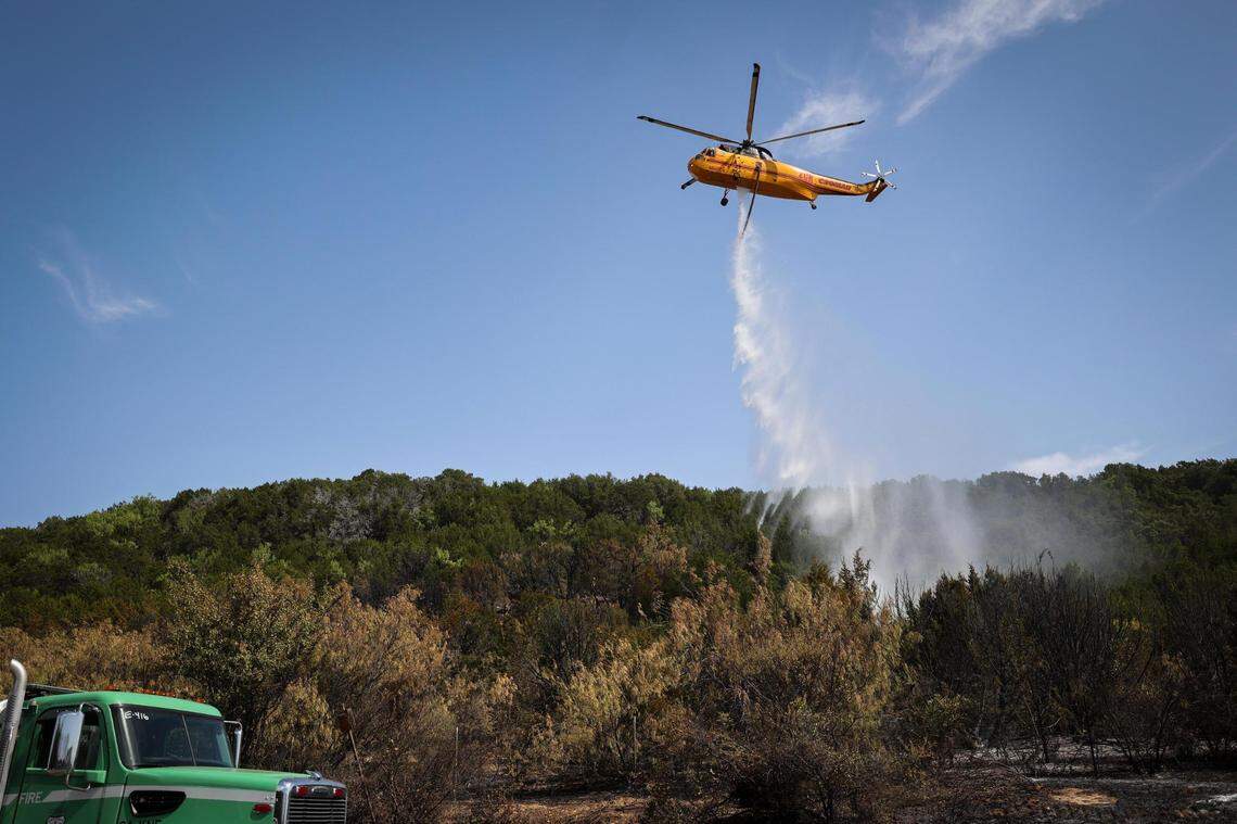 A helicopter drops lake water on a blaze along FM 1148 on Tuesday, July 19, 2022, near Possum Kingdom Lake in Graham. The fire has consumed 500 acres.