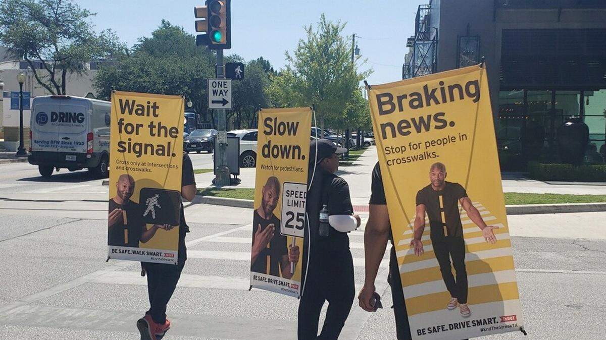 A street team with the Texas Department of Transportation marched around Sundance Square on Thursday carrying signs to promote pedestrian safety.