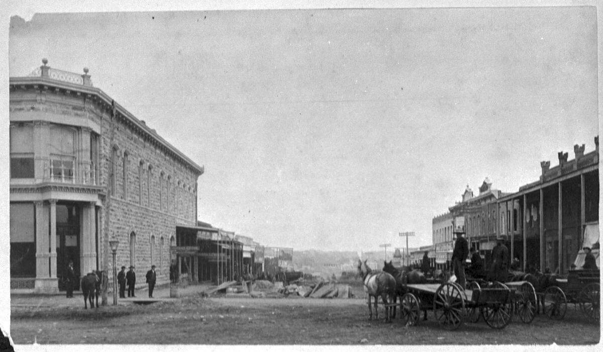1884: Weatherford’s Courthouse Square, with piles of stones for curbing. Citizens’ National Bank, left, and Merchants and Farmers National Bank on right.