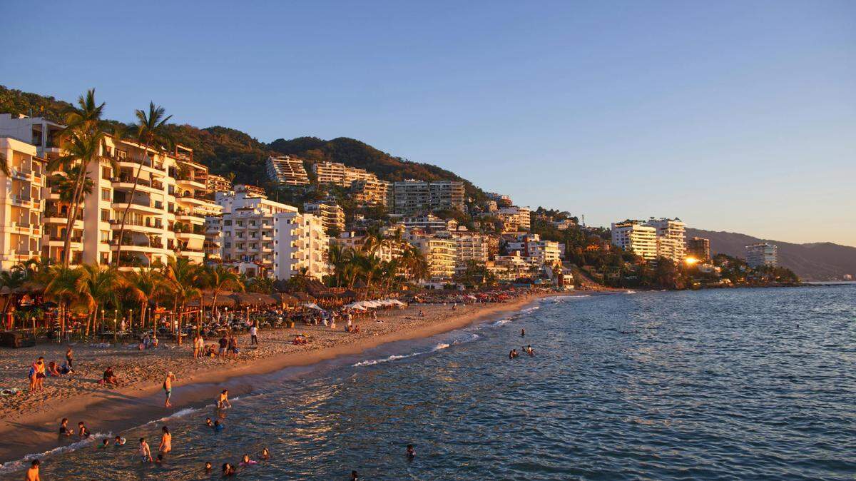 Puerto Vallarta coast glows during golden hour. Beaches along the hotel zone are flocked with tourists.