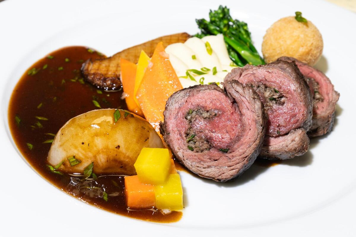 The Spinalis Dorsi Roulade with mushroom and spinach filling, whipped potato and parsnip, sautéed vegetable medley with pan-seared maitake mushroom, potato and blue cheese croquette, glazed cipollini onion, in a madeira sauce.